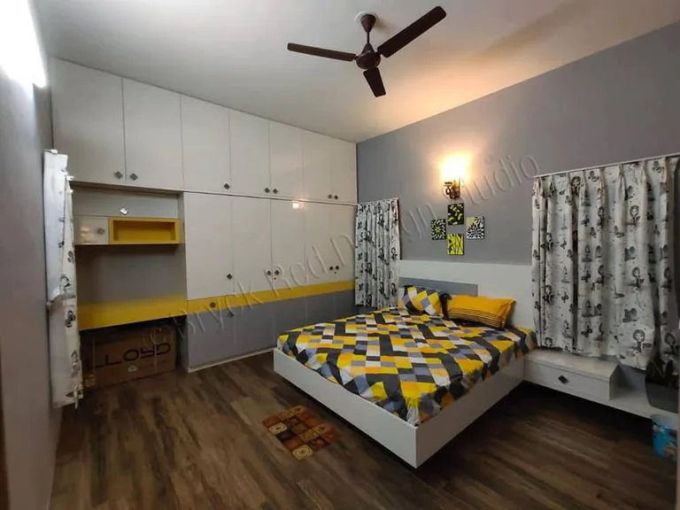 Dharwad bedroom with yellow accents, patterned bedding and integrated white cabinetry