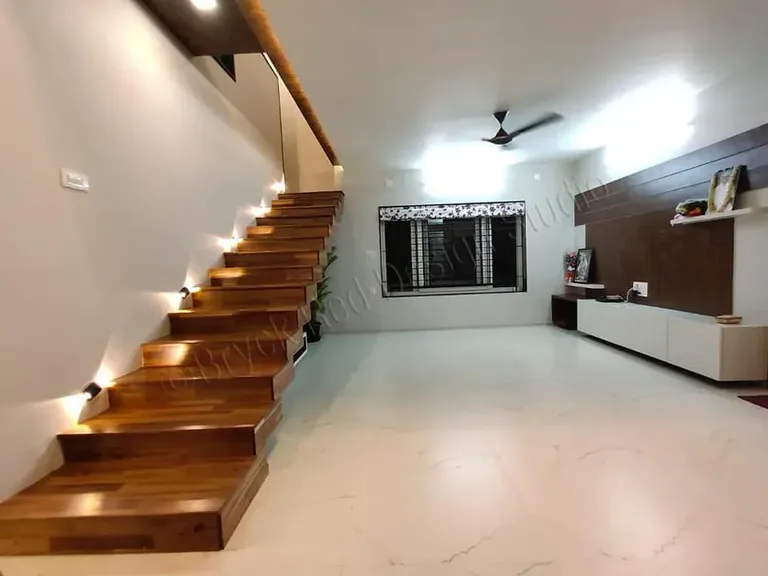 Open-tread timber staircase rising against a white wall.