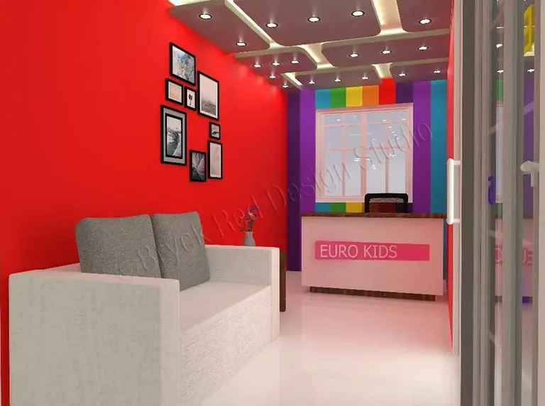 Reception with a red wall, framed picture cluster and a pink desk against rainbow-striped panelling.